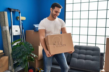Photo for Young hispanic man smiling confident holding kitchen cardboard box at new home - Royalty Free Image