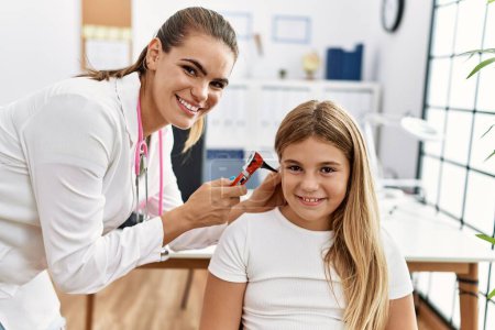 Photo for Woman and girl doctor and patient examining ear using otoscope at clinic - Royalty Free Image