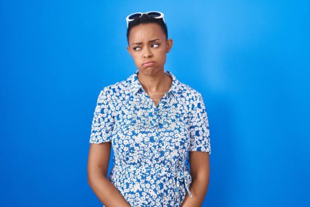 Photo for African american woman standing over blue background looking sleepy and tired, exhausted for fatigue and hangover, lazy eyes in the morning. - Royalty Free Image