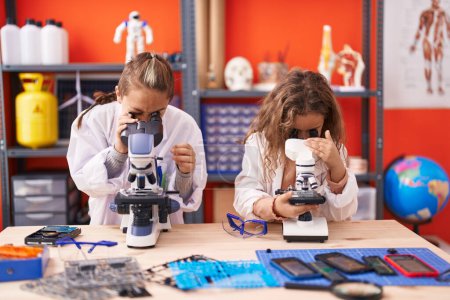 Foto de Dos niños estudiantes usando microscopios de pie en el aula de laboratorio - Imagen libre de derechos