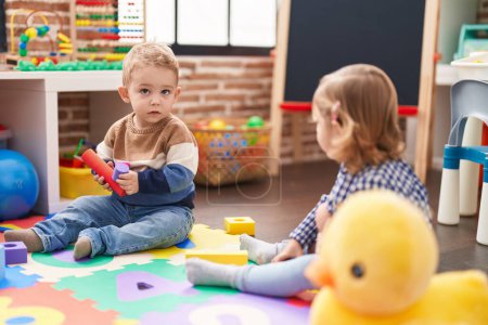 Photo for Two kids playing with construction blocks sitting on floor at kindergarten - Royalty Free Image