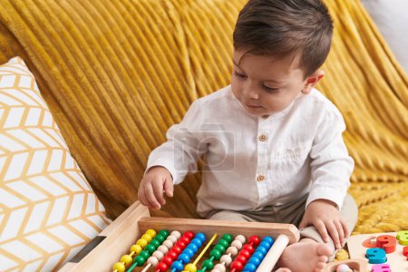 Photo for Adorable hispanic boy playing with abacus sitting on sofa at home - Royalty Free Image