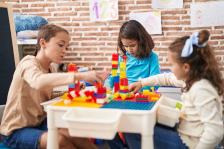 Foto de Group of kids playing with construction blocks sitting on table at kindergarten - Imagen libre de derechos