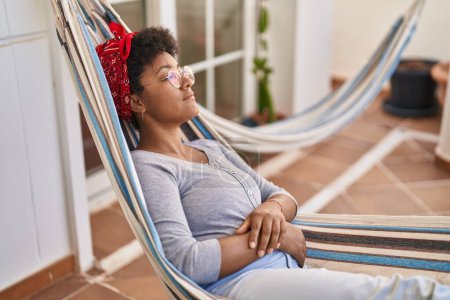 Téléchargez les photos : African american woman lying on hammock sleeping at home terrace - en image libre de droit