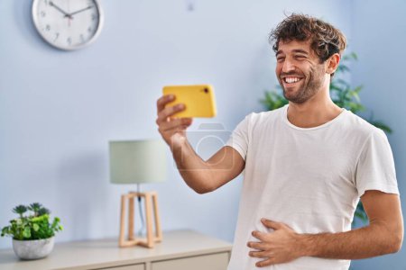 Téléchargez les photos : Jeune homme souriant confiant regarder la vidéo sur smartphone à la maison - en image libre de droit