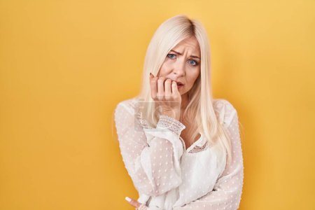 Photo for Caucasian woman standing over yellow background looking stressed and nervous with hands on mouth biting nails. anxiety problem. - Royalty Free Image