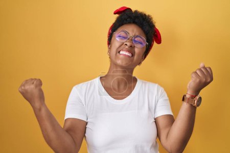 Photo for Young african american woman standing over yellow background celebrating surprised and amazed for success with arms raised and eyes closed. winner concept. - Royalty Free Image
