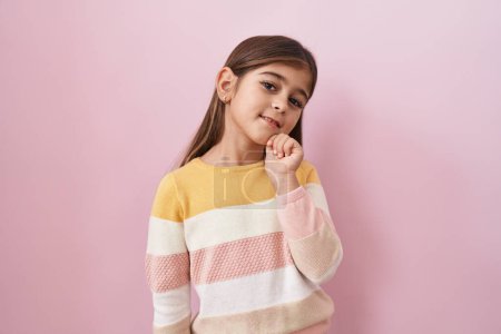Photo for Little hispanic girl wearing sweater over pink background thinking concentrated about doubt with finger on chin and looking up wondering - Royalty Free Image