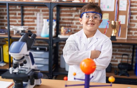 Foto de Adorable estudiante hispano sonriendo confiado de pie con los brazos cruzados gesto en el aula de laboratorio - Imagen libre de derechos