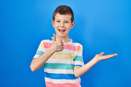Téléchargez les photos : Jeune enfant caucasien debout sur fond bleu montrant la main de la paume et faisant un geste correct avec les pouces levés, souriant heureux et joyeux - en image libre de droit