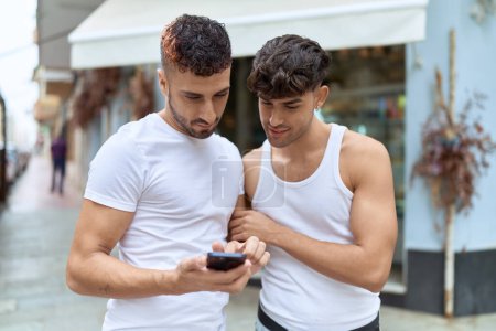Téléchargez les photos : Two hispanic men couple smiling confident using smartphone at coffee shop terrace - en image libre de droit