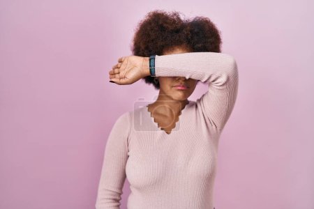 Téléchargez les photos : Young african american woman standing over pink background covering eyes with arm, looking serious and sad. sightless, hiding and rejection concept - en image libre de droit