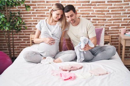 Foto de Hombre y mujer pareja sosteniendo muñeca al bebé sentado en la cama en el dormitorio - Imagen libre de derechos