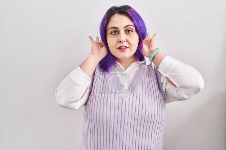Photo for Plus size woman wit purple hair standing over white background trying to hear both hands on ear gesture, curious for gossip. hearing problem, deaf - Royalty Free Image