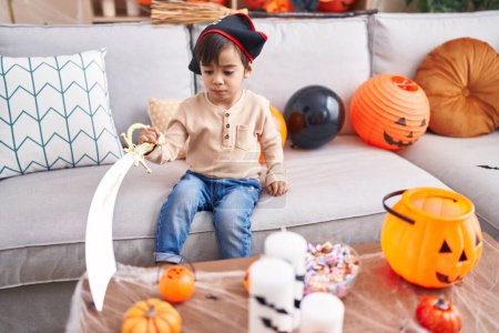 Photo for Adorable hispanic boy having halloween party holding sword at home - Royalty Free Image