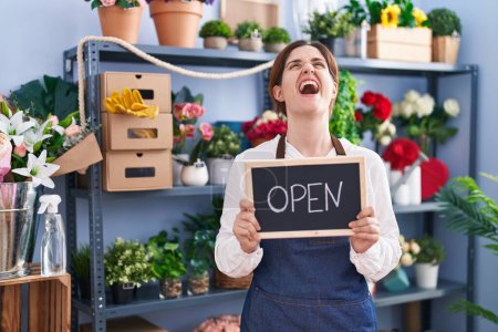 Photo for Brunette woman working at florist holding open sign angry and mad screaming frustrated and furious, shouting with anger looking up. - Royalty Free Image