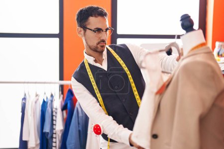 Photo for Young hispanic man tailor holding t shirt standing by manikin at atelier - Royalty Free Image