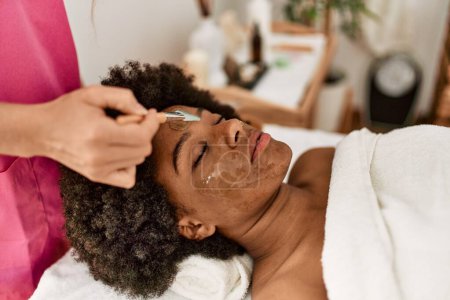 Photo for Young african american woman having facial treatment at beauty center - Royalty Free Image
