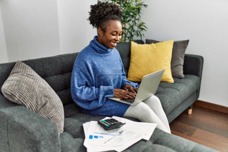 Foto de African american woman using laptop accounting at home - Imagen libre de derechos