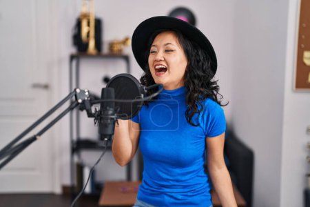 Photo for Young chinese woman artist singing song at music studio - Royalty Free Image