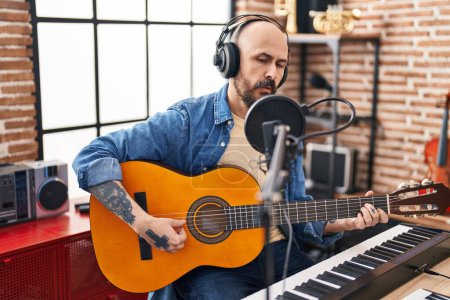 Foto de Joven hombre calvo músico cantando canción tocando guitarra clásica en el estudio de música - Imagen libre de derechos