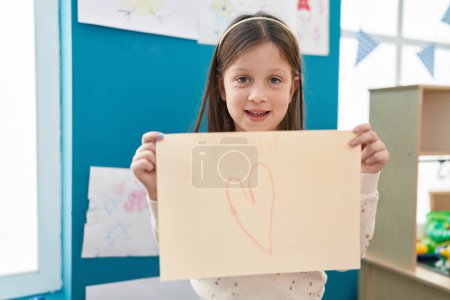 Téléchargez les photos : Adorable fille hispanique préscolaire étudiant tenant le coeur dessiner à la maternelle - en image libre de droit