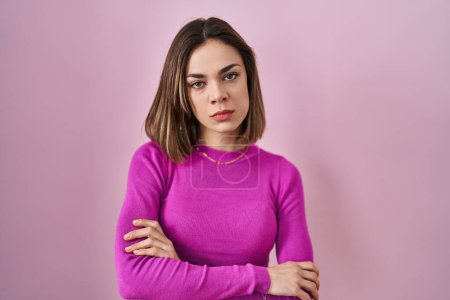 Téléchargez les photos : Hispanic woman standing over pink background skeptic and nervous, disapproving expression on face with crossed arms. negative person. - en image libre de droit