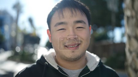 Téléchargez les photos : Young chinese man smiling confident standing at street - en image libre de droit