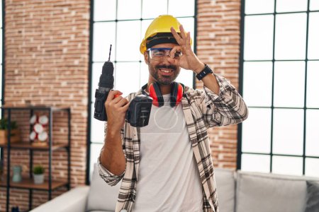 Photo for Young hispanic man with beard working at home renovation smiling happy doing ok sign with hand on eye looking through fingers - Royalty Free Image