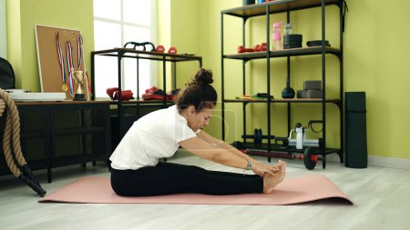 Téléchargez les photos : Middle age hispanic woman training yoga sitting on floor at sport center - en image libre de droit
