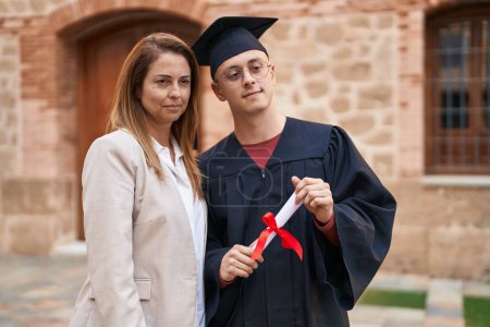 Foto de Hombre y mujer madre e hijo graduado de pie junto con la expresión relajada en la universidad - Imagen libre de derechos
