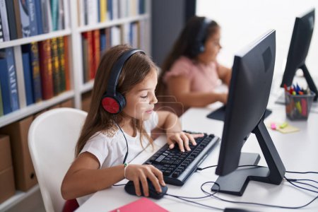 Foto de Dos estudiantes de niños usando auriculares usando computadora estudiando en el aula - Imagen libre de derechos