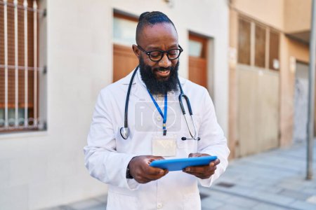 Foto de Joven afroamericano vistiendo uniforme médico usando touchpad en el hospital - Imagen libre de derechos
