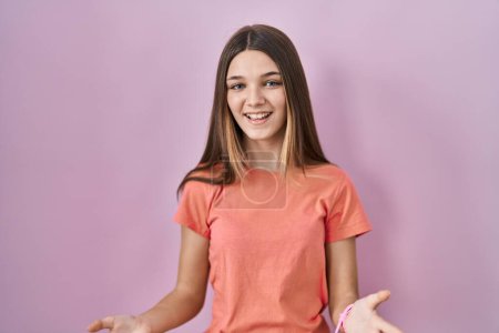 Téléchargez les photos : Adolescente debout sur fond rose souriant gai avec les bras ouverts comme accueil amical, salutations positives et confiantes - en image libre de droit