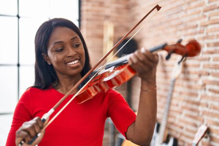 Téléchargez les photos : Young african american woman musician playing violin at music studio - en image libre de droit