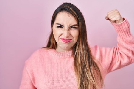 Photo for Young hispanic woman standing over pink background strong person showing arm muscle, confident and proud of power - Royalty Free Image