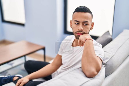 Photo for African american man sitting on sofa with serious expression at home - Royalty Free Image