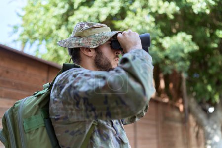Foto de Joven hispano con uniforme de soldado usando prismáticos en el parque - Imagen libre de derechos