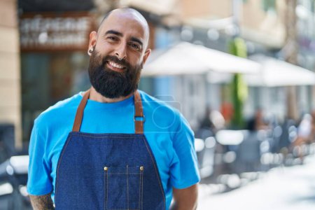 Foto de Young bald man waiter smiling confident standing at coffee shop terrace - Imagen libre de derechos