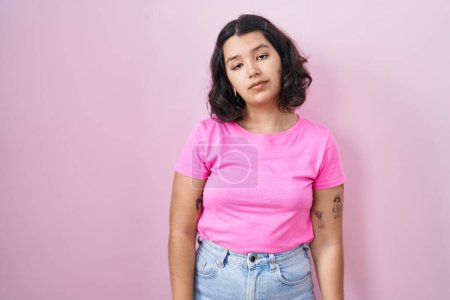 Photo for Young hispanic woman standing over pink background looking sleepy and tired, exhausted for fatigue and hangover, lazy eyes in the morning. - Royalty Free Image