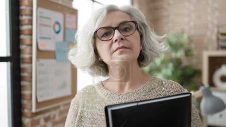 Téléchargez les photos : Middle age woman with grey hair business worker holding binder at office - en image libre de droit