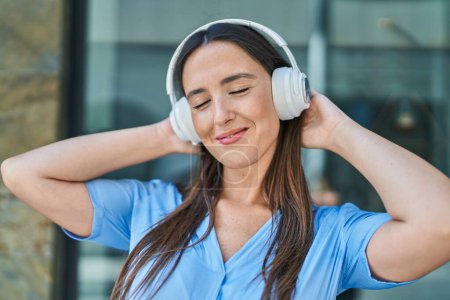Photo for Young beautiful hispanic woman smiling confident listening to music at street - Royalty Free Image