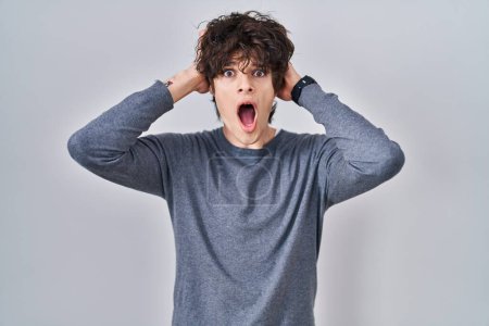 Photo for Young man standing over isolated background crazy and scared with hands on head, afraid and surprised of shock with open mouth - Royalty Free Image