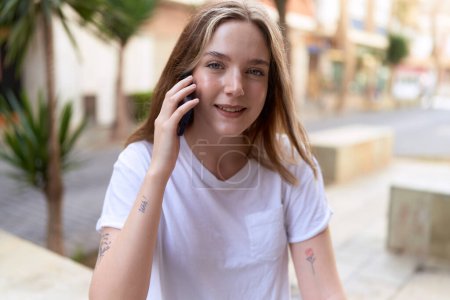 Foto de Mujer caucásica joven sonriendo confiado hablando en el teléfono inteligente en la calle - Imagen libre de derechos