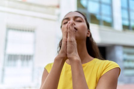 Photo for Young african american woman praying with closed eyes at street - Royalty Free Image