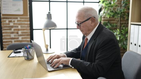 Téléchargez les photos : Travailleur d'affaires senior travaillant avec un ordinateur portable au bureau - en image libre de droit