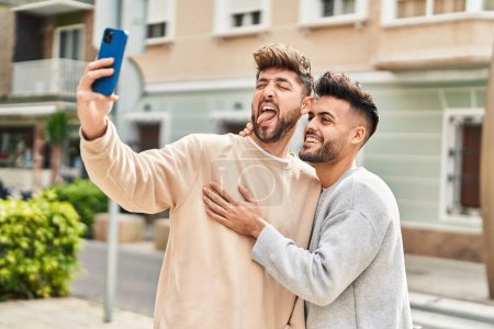 Téléchargez les photos : Jeune couple se câlinant faisant du selfie par le smartphone à la rue - en image libre de droit