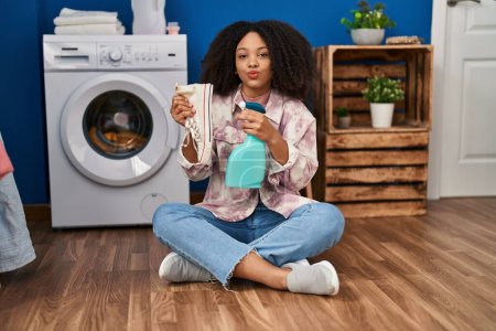 Foto de Joven mujer afroamericana limpiando zapatos en la lavandería mirando a la cámara soplando un beso siendo encantadora y sexy. expresión de amor. - Imagen libre de derechos