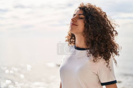 Foto de Young hispanic woman smiling confident breathing at seaside - Imagen libre de derechos