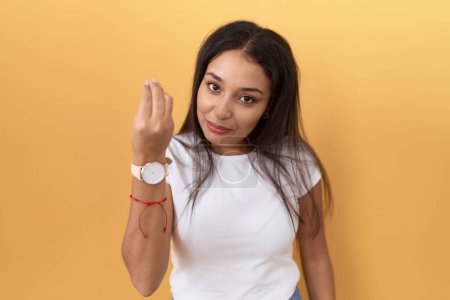 Photo for Young arab woman wearing casual white t shirt over yellow background doing italian gesture with hand and fingers confident expression - Royalty Free Image